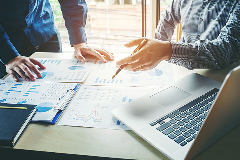 Two businessmen shaking hands with a group of business people in the background.